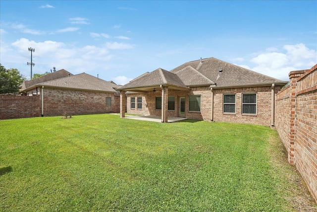 back of house featuring a patio, roof with shingles, a yard, and a fenced backyard
