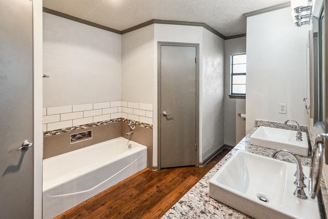 bathroom with a sink, a bath, crown molding, and wood finished floors