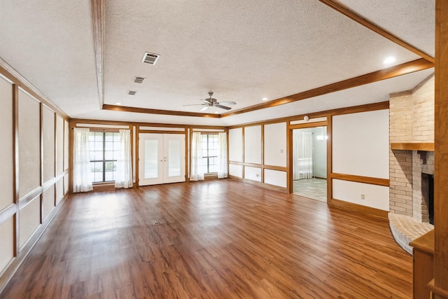 unfurnished living room featuring french doors, a ceiling fan, a fireplace, wood finished floors, and visible vents