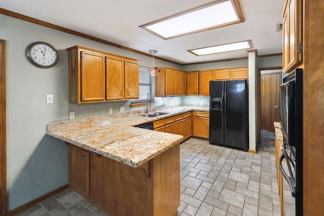 kitchen featuring crown molding, a peninsula, a sink, black fridge, and light stone counters