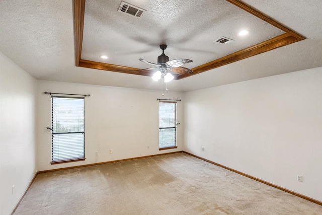 spare room featuring a tray ceiling, visible vents, ceiling fan, and light colored carpet