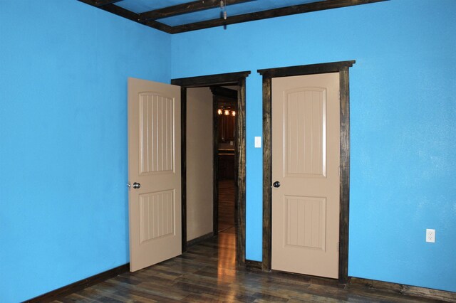 spare room featuring dark wood-style floors and baseboards