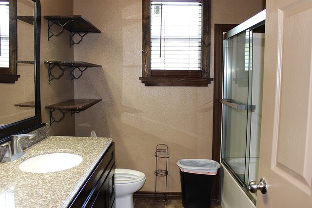 bathroom featuring toilet, vanity, a textured wall, and baseboards
