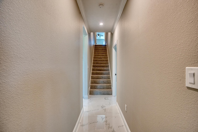 corridor with a textured wall, baseboards, stairs, marble finish floor, and ornamental molding