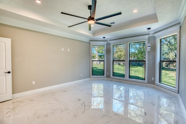 empty room with ornamental molding, marble finish floor, a tray ceiling, and baseboards