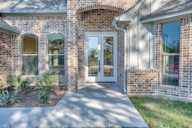 view of exterior entry with brick siding and roof with shingles