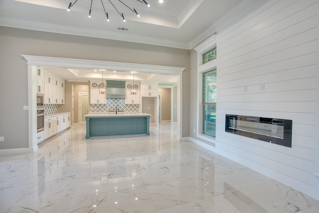 kitchen featuring stainless steel appliances, a tray ceiling, visible vents, and decorative backsplash