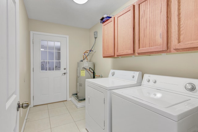 washroom with electric water heater, independent washer and dryer, cabinets, and light tile patterned flooring