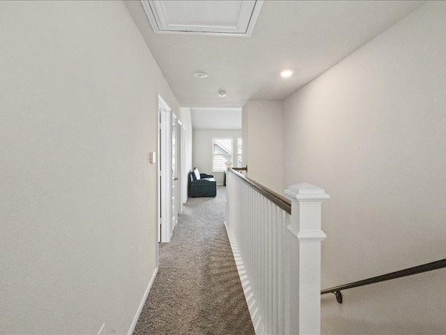 hall with baseboards, light carpet, and an upstairs landing