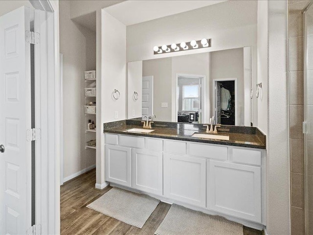full bath featuring a sink, double vanity, ensuite bath, and wood finished floors