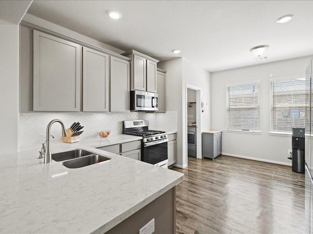 kitchen featuring a sink, gray cabinets, appliances with stainless steel finishes, and light stone countertops