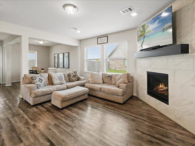 living area featuring recessed lighting, visible vents, dark wood-style floors, and a tile fireplace