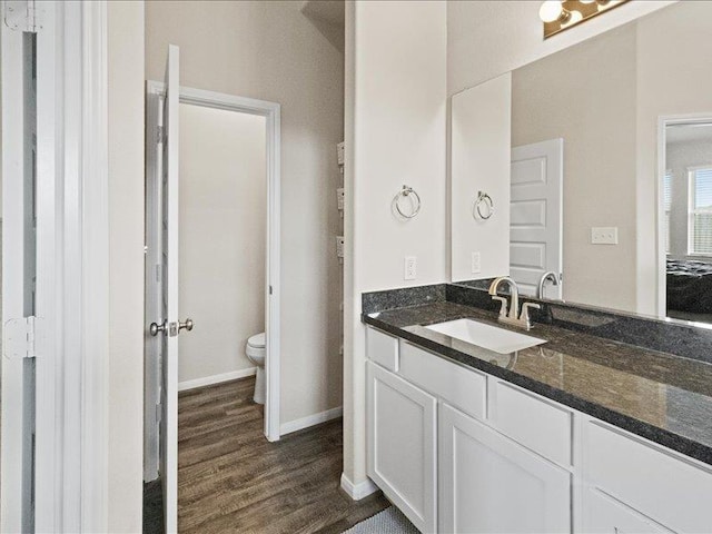 bathroom with vanity, baseboards, toilet, and wood finished floors