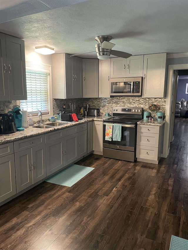 748 Queens Ct, Port Arthur, TX 77642 - kitchen featuring stainless steel appliances, dark wood-style flooring, decorative backsplash, a ceiling fan, and gray cabinets