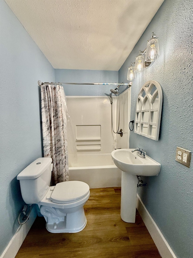 176 County Road 753, Buna, TX 77612 - full bathroom with toilet, wood finished floors, baseboards, a textured ceiling, and shower / bath combo with shower curtain