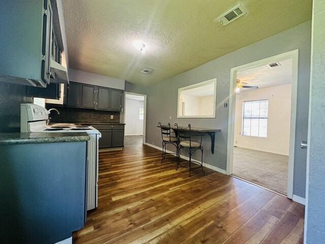 2922 Little Cypress Dr, Orange, TX 77632 - kitchen with white range with electric cooktop, dark wood-style flooring, a textured ceiling, a ceiling fan, and dark countertops