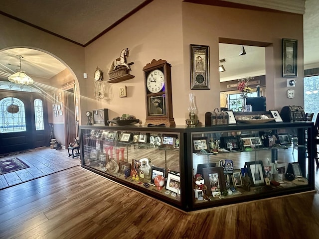 bar with an inviting chandelier, wood-type flooring, crown molding, and a healthy amount of sunlight