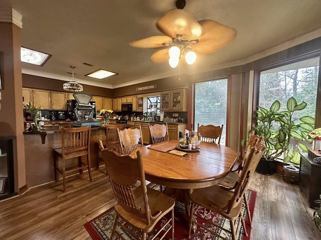 dining area with ceiling fan, a skylight, crown molding, and dark hardwood / wood-style floors