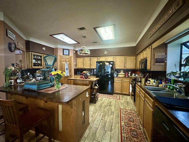 kitchen featuring sink, black appliances, ornamental molding, and a breakfast bar area