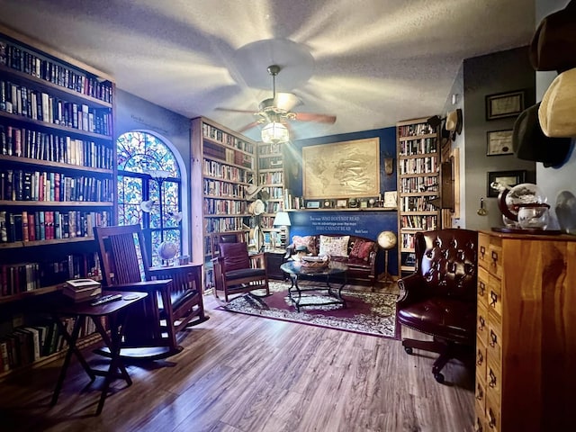 living area with hardwood / wood-style flooring, a textured ceiling, built in features, and ceiling fan