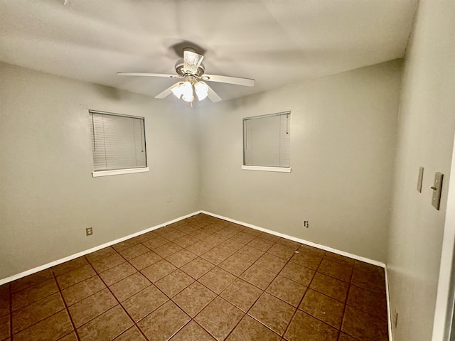 spare room featuring ceiling fan and dark tile patterned flooring