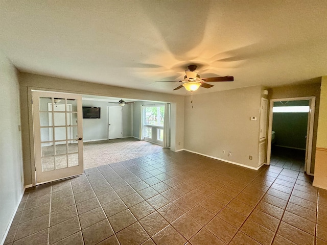 unfurnished room featuring ceiling fan, dark tile patterned floors, a textured ceiling, and french doors