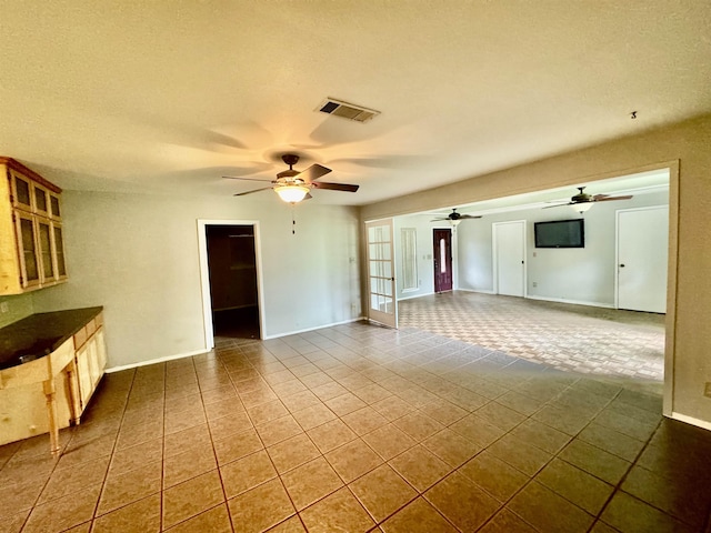 unfurnished living room with tile patterned flooring, french doors, and ceiling fan