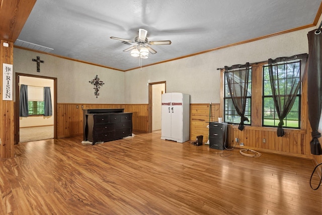 10425 Bussey Rd, Silsbee, TX 77656 - unfurnished living room featuring wood finished floors, a ceiling fan, wood walls, a wainscoted wall, and a textured ceiling