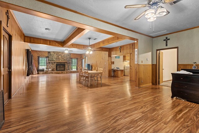 10425 Bussey Rd, Silsbee, TX 77656 - living room with a ceiling fan, wood walls, wood finished floors, a stone fireplace, and beam ceiling