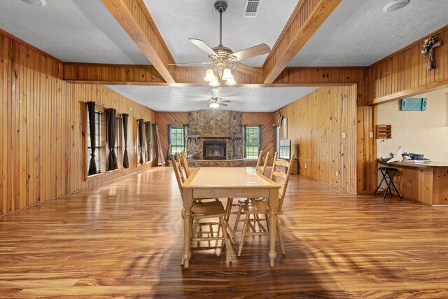 10425 Bussey Rd, Silsbee, TX 77656 - dining room with wooden walls, wood finished floors, a ceiling fan, beamed ceiling, and a fireplace