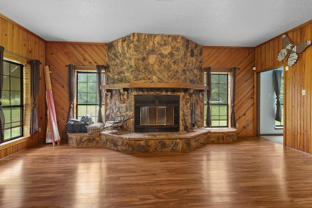 10425 Bussey Rd, Silsbee, TX 77656 - unfurnished living room featuring wooden walls, healthy amount of natural light, a textured ceiling, hardwood / wood-style floors, and a fireplace