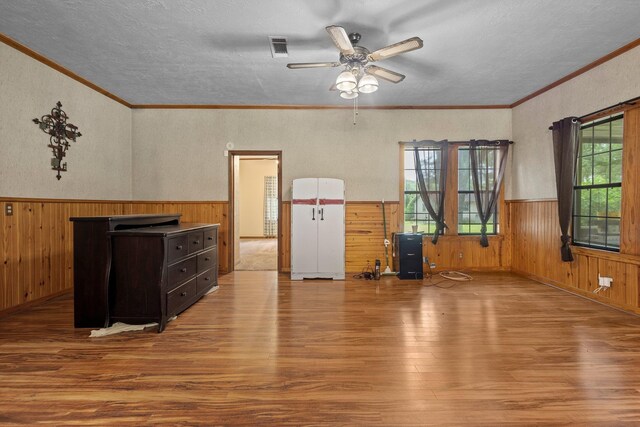 10425 Bussey Rd, Silsbee, TX 77656 - living area featuring wainscoting, wood finished floors, ceiling fan, wooden walls, and a textured ceiling