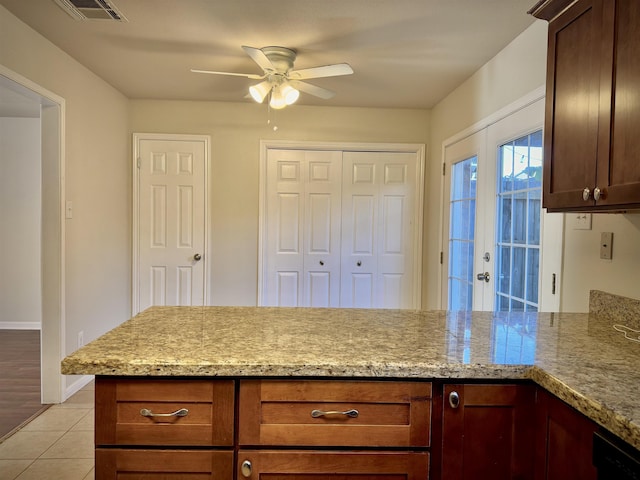 kitchen with ceiling fan, french doors, light stone counters, kitchen peninsula, and light tile patterned floors