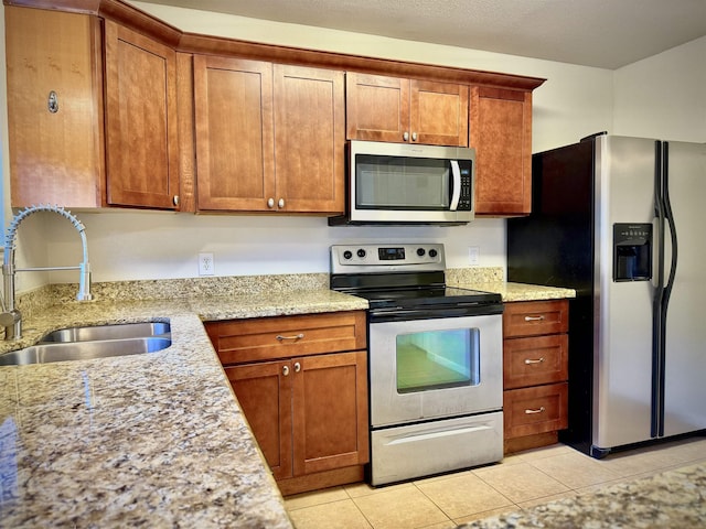 kitchen featuring light stone counters, sink, light tile patterned floors, and stainless steel appliances