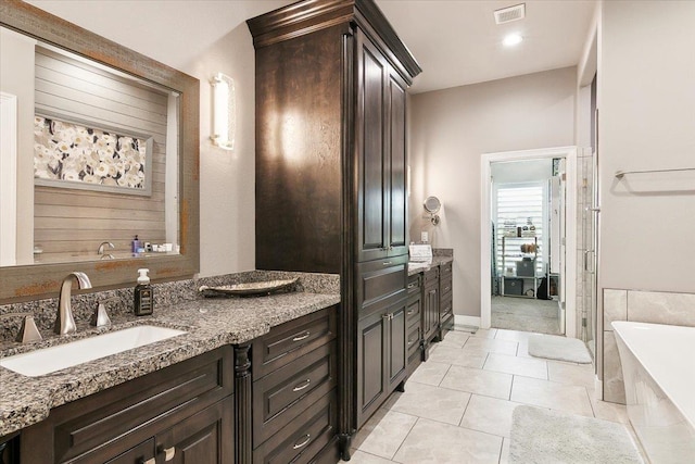 bathroom with a bathing tub, tile patterned flooring, and vanity