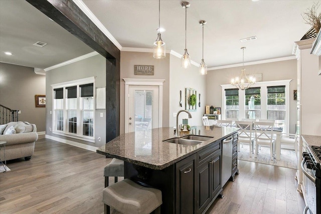 kitchen with sink, an island with sink, stone countertops, a kitchen bar, and hardwood / wood-style flooring