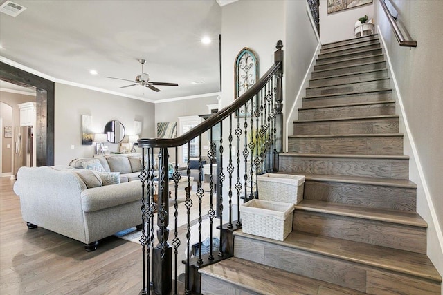 staircase with ceiling fan, crown molding, and wood-type flooring