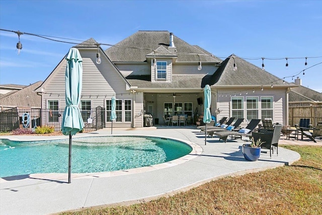 rear view of house featuring a fenced in pool, ceiling fan, and a patio