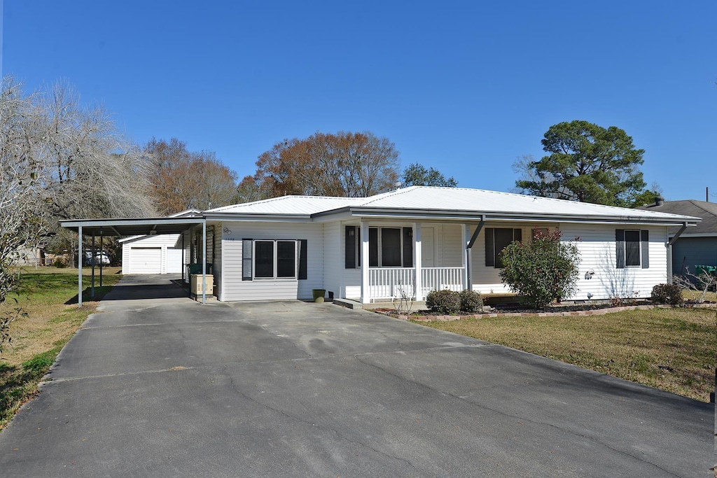 single story home with a porch, a garage, a carport, and a front lawn