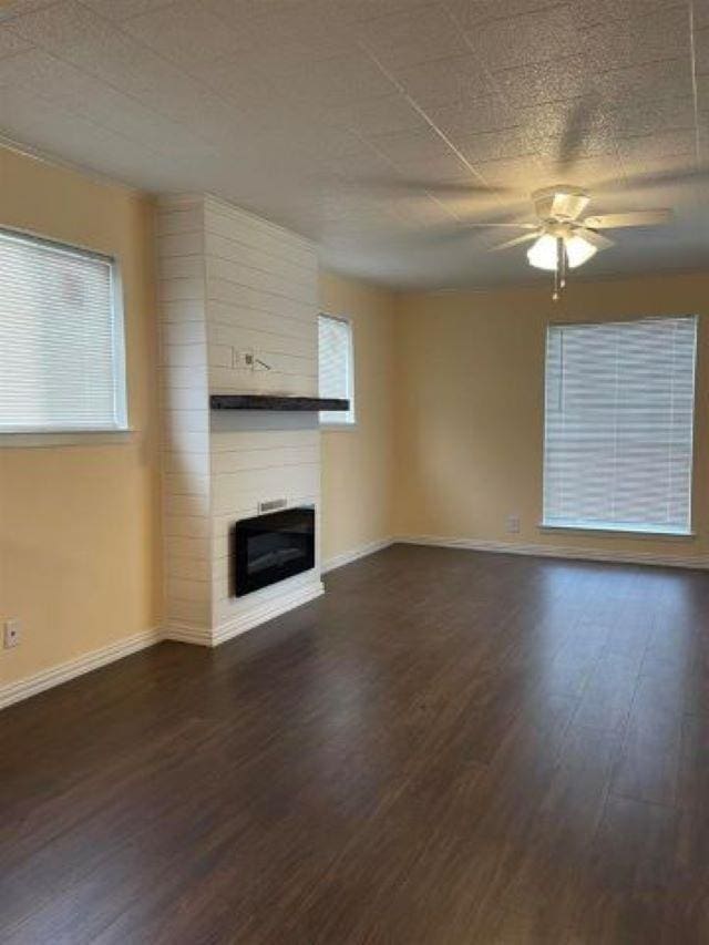 unfurnished living room with a fireplace, dark hardwood / wood-style flooring, and ceiling fan