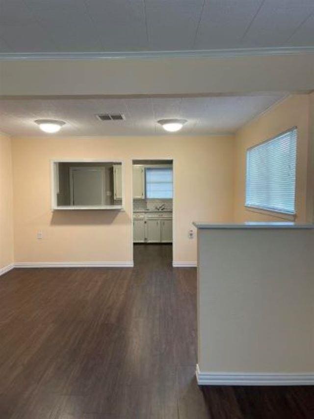 spare room with dark wood-type flooring and crown molding