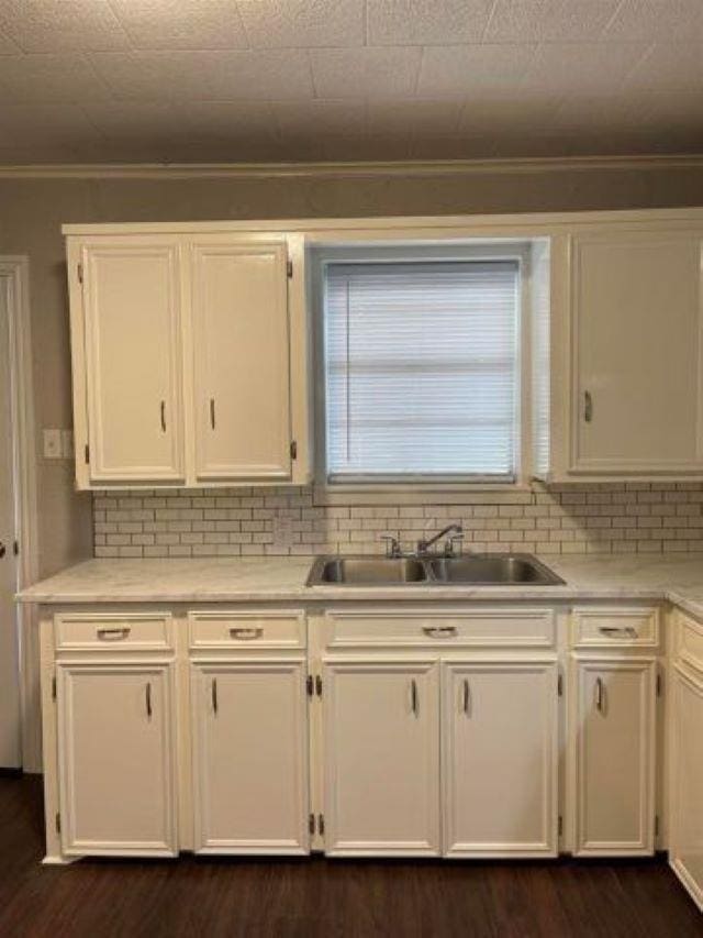 kitchen with tasteful backsplash, white cabinetry, dark wood-type flooring, and sink