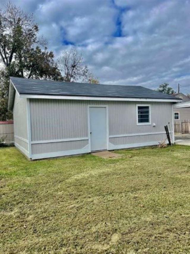 back of property featuring a yard and an outdoor structure