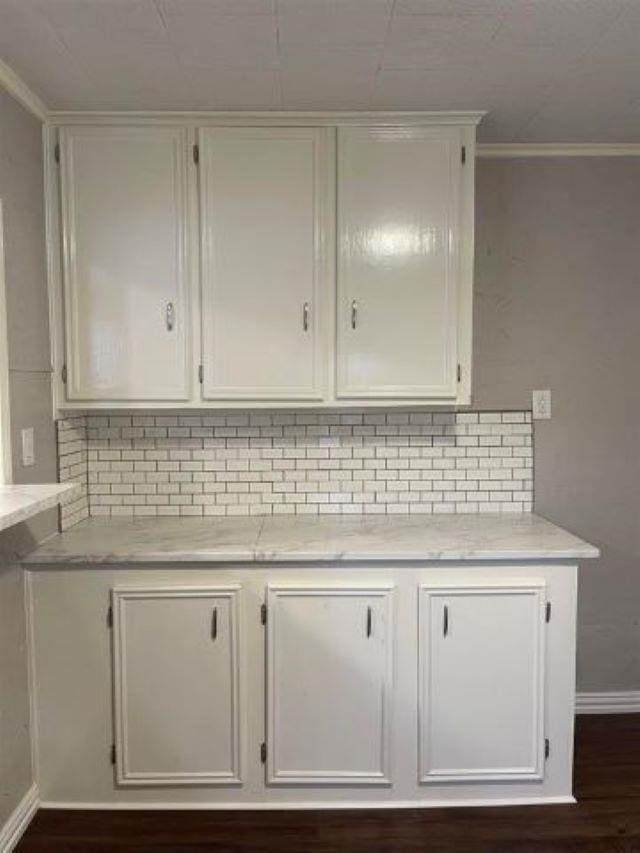 interior space with backsplash, crown molding, and hardwood / wood-style flooring