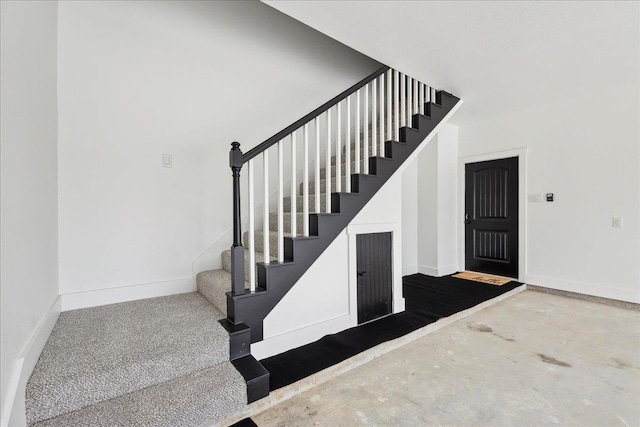 stairway with unfinished concrete flooring and baseboards