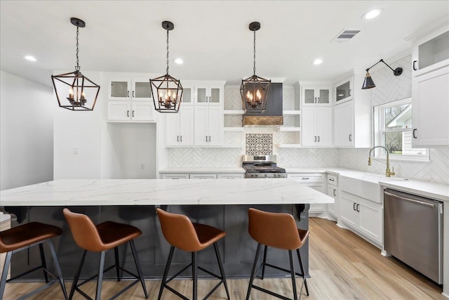 kitchen featuring visible vents, open shelves, a sink, stainless steel appliances, and light wood-style floors