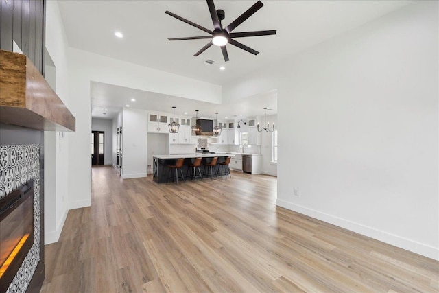 unfurnished living room with a ceiling fan, baseboards, light wood-style flooring, recessed lighting, and a tile fireplace