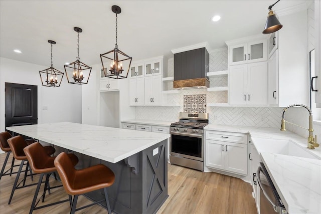 kitchen featuring open shelves, a center island, light wood-style flooring, stainless steel appliances, and a sink