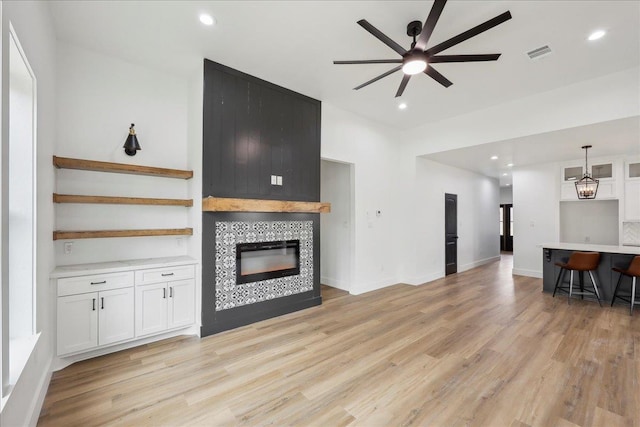 living room with recessed lighting, light wood-type flooring, ceiling fan, and a tile fireplace