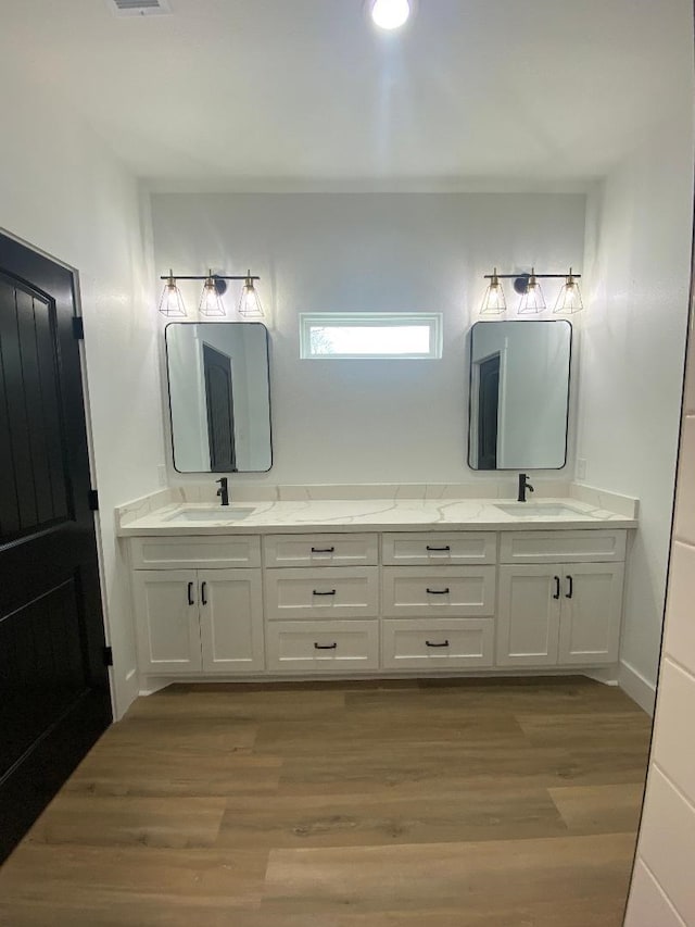 full bath with double vanity, wood finished floors, and a sink